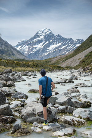 Young male photographer look up to Mount Cook, major tourism spot in summer of South Island, New Zealand while hiking to vista point.の写真素材