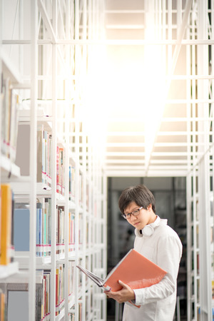 Young Asian man university student reading book in library, education research and self learning in university life conceptsの写真素材