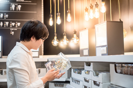 Young Asian man choosing package of electrical light bulb, furniture home decoration shopping conceptの写真素材