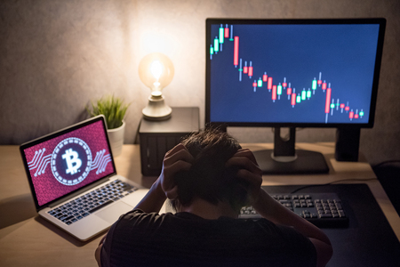 Male Investor feeling stressed and frustrated due to access denied of bitcoin system with candlestick graph price down on laptop screen. Bitcoin cryptocurrency digital money crisis conceptの写真素材