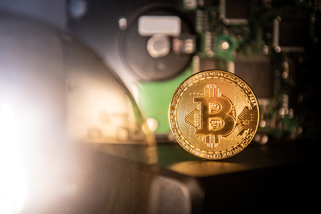 Bitcoin gold coin with blurry hard disk in the background. Worldwide cryptocurrency and online payment with digital currency conceptsの写真素材