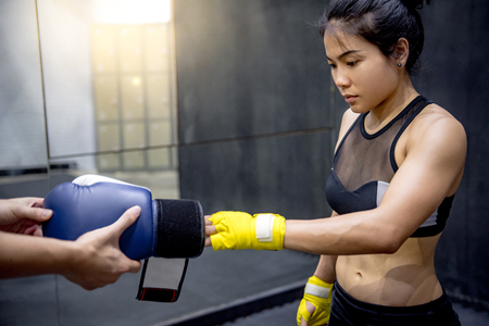 Trainer hand help Asian femlae boxer wearing boxing gloves in the gym. Boxing training conceptの写真素材