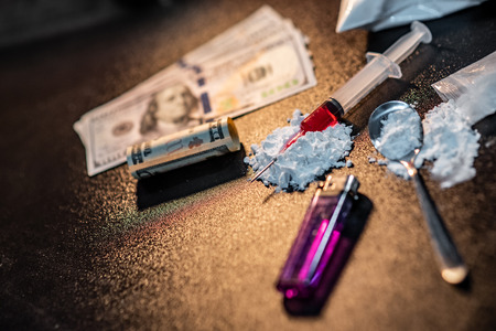 Drug injection syringe on heroin powder. Spoon with cigarette lighter for heroin cooking and money on dark table. Drug addiction conceptの写真素材