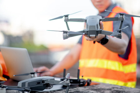 Young Asian engineer man working with drone laptop and smartphone at construction site. Using...