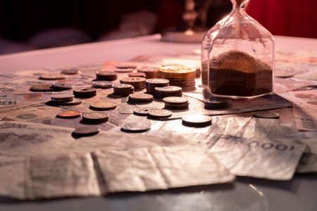 Sand running through the shape of hourglass on table with banknotes and coins of international...