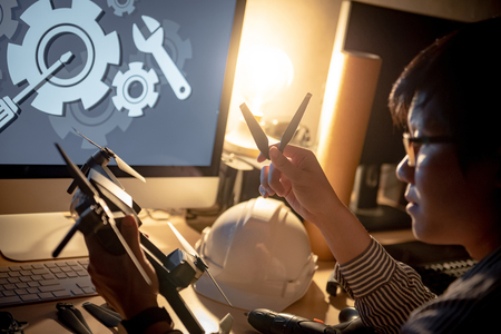 Asian technical engineer changing spare propeller repairing drone with fixing tools on the desk. Male technician maintenance drone. Unmanned aerial vehicle (UAV) photography and engineering conceptの写真素材