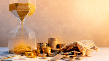 Sand running through the shape of hourglass with banknotes and coins stack of international currency...