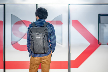 Young Asian man standing in front of the metro train on station platform in the city. Urban lifestyle conceptの写真素材