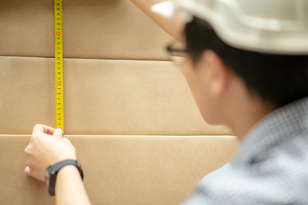 Male worker hand using tape measure for measuring dimension of product in cardboard box. Shopping lifestyle in warehouse conceptの写真素材