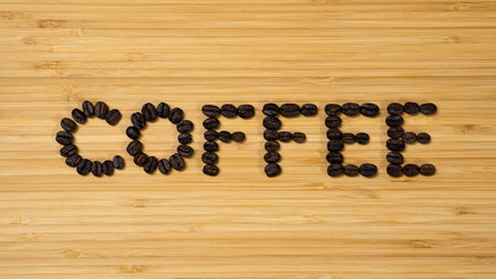 Coffee word made from coffee beans on wooden background. Top view of wood table.の写真素材
