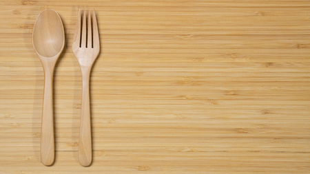Wooden spoon and fork on wood table background. Top view. Eating food in the restaurant conceptの写真素材