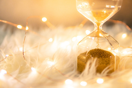 Gold sand running through the shape of hourglass on white flur carpet.Time passing and running out of time. Urgency countdown timer for business deadline conceptの写真素材