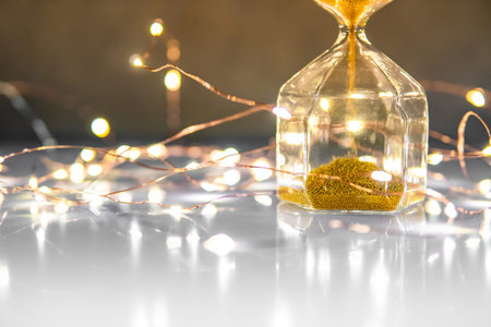 Gold sand running through the shape of hourglass on glossy table.Time passing and running out of...
