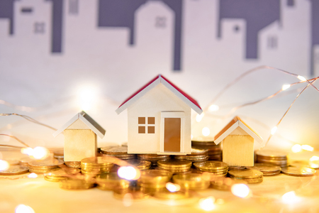 Real estate or property investment concept. Home mortgage loan rate. Gold coins stack, house models and decorative Christmas lights on the table. Saving money for future retirement.の写真素材