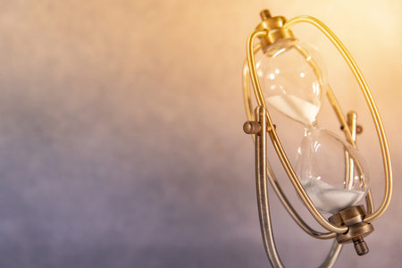 White sand running through the shape of vintage hourglass.Time passing and running out of time....