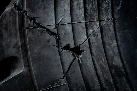 Old cracked rubber tire texture. Abstract damaged black surface background. Tire tread problem and solution conceptの写真素材