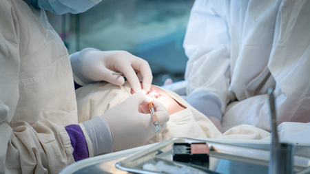 Female dentist and assistant hand using medicine syringe and other instruments for examining and curing patient teeth in dental clinic. Dental procedure and medical treatment.の写真素材