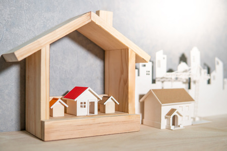 Property or real estate investment concept. Home mortgage loan rate. Saving money for future retirement. Miniature house model with paper city background and construction crane on wooden table.の写真素材