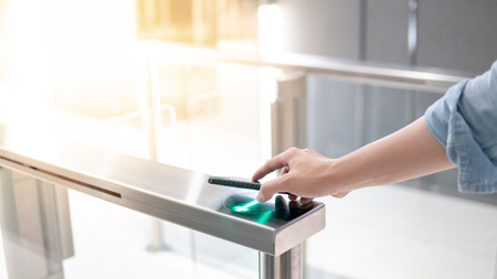 Male hand using smartphone to open automatic gate machine in office buildingの写真素材