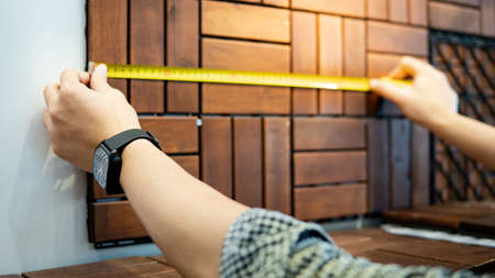 Male worker hand using tape measure for measuring dimension of wooden floor pavement block pattern mockup. Shopping lifestyle in warehouse conceptの写真素材