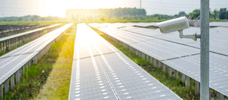 CCTV camera monitoring solar panels or polycrystalline silicon solar cells in the farm. Security in solar power plant. Photovoltaic modules for renewable energyの写真素材