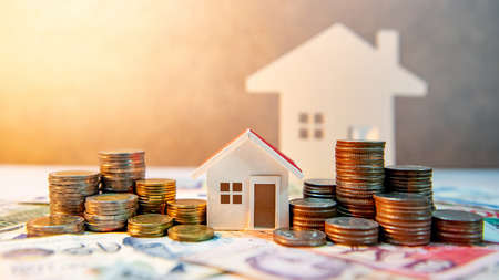 Real estate or property investment. Home mortgage loan rate. Saving money for retirement concept. Coin stack on international banknotes with house model on table. Business growth backgroundの写真素材