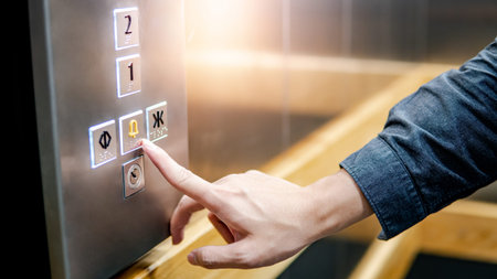 Male forefinger pressing on emergency stop and alarm button in elevator (lift). Mechanical...