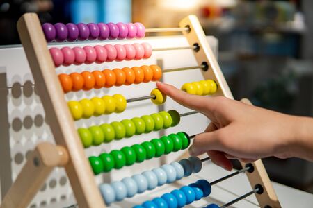 Male hand calculating with beads on wooden rainbow abacus for number calculation. Mathematics learning conceptの写真素材