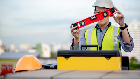 Asian maintenance worker man holding red aluminium spirit level tool or bubble levels over tool box...