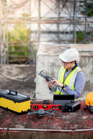 Asian engineer man working with drone, laptop and working tools at construction site. Male worker...