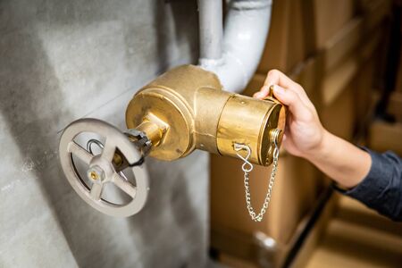 Male hand technician man checking water gate valve for hydrant system in factory by using digital tablet. Building fire protection service and maintenance conceptsの写真素材