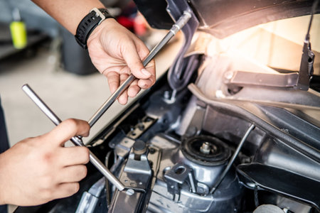 Male hand of auto mechanic fixing car hood and engine in the garage. Automobile industry concept
