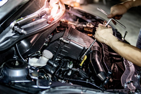 Male hand of auto mechanic fixing car engine in the garage. Automobile industry concept