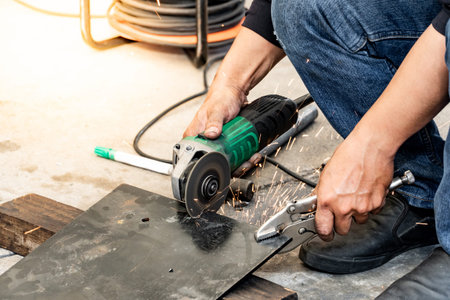 Male auto mechanic hand using angle grinder and adjustable spanner wrench for cutting steel plate...