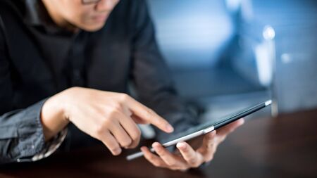 Young Asian businessman using digital tablet in office meeting room. Male entrepreneur reading news on social media app. Online marketing and Big data technology for E-commerce business. の写真素材