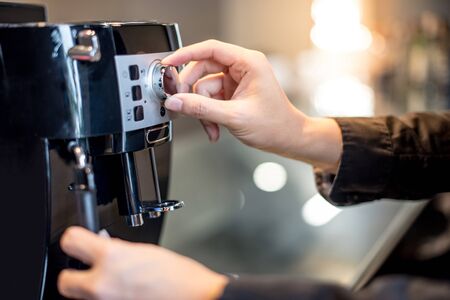Male barista hand turning button on coffee machine in the kitchen. Making coffee conceptの写真素材