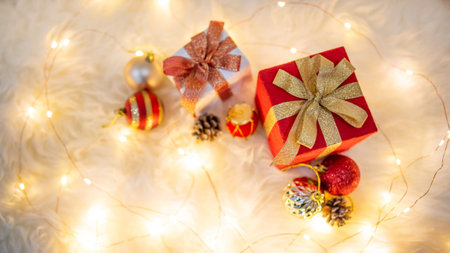 Christmas decoration on white hairy carpet with illuminated lights. Gift box with ribbon, glossy...