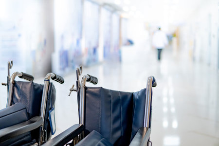 Group of blue folding wheelchair with blurred doctor and nurse walking through the corridor in...