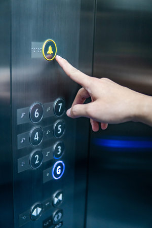 Male forefinger pressing on emergency stop and alarm button in elevator (lift). Mechanical...