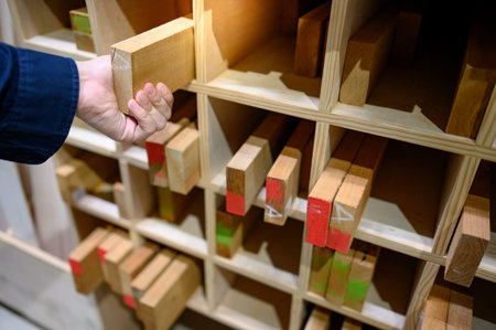 Male hand choosing wood lumber from wooden shelf in factory. Wood industry concept