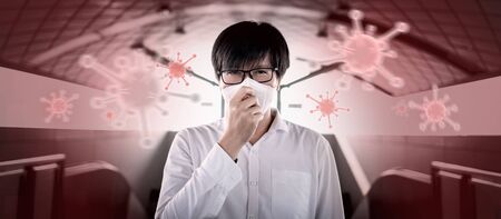 COVID-19 pandemic or Coronavirus infection concept. Asian man coughing with floating virus pathogen on red background. Respiratory droplets transmission protection by wearing face mask.の写真素材