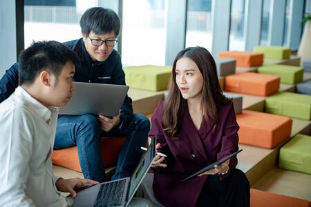 Business meeting and teamwork concept. Asian businesswoman explaining project data report to colleagues using digital tablet for presentation at workplace. Coworkers team brainstorming ideas in officeの写真素材