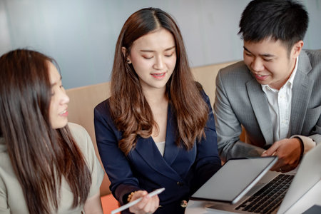 Business meeting and teamwork concept. Asian colleagues discussing about project report using laptop computer and digital tablet at workplace. Coworkers team brainstorming ideas in office boardroom.の写真素材