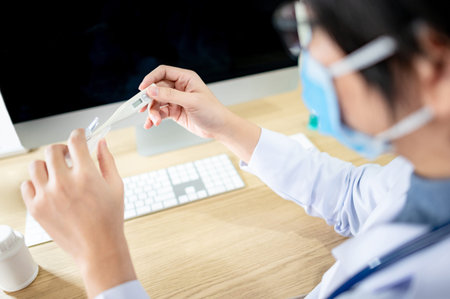 Measure body temperature concept. Doctor or physician holding digital thermometer while sitting with...