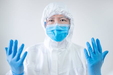 Doctor or physician in personal protective equipment showing sterile rubber gloves in hospital clinic. Medical worker wearing PPE suit, mask and goggles for preventing Coronavirus (COVID-19) infectionの写真素材