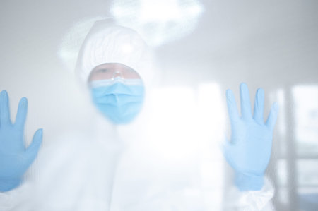 Doctor or physician in personal protective equipment standing behind the door in hospital clinic....