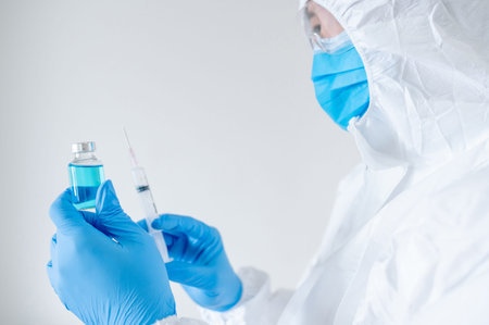 COVID-19 Vaccination concept. Doctor or physician in Personal protective equipment suit (PPE) with...