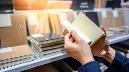 Male hand customer choosing new paper notebook from display rack in stationery shop. Buying office...