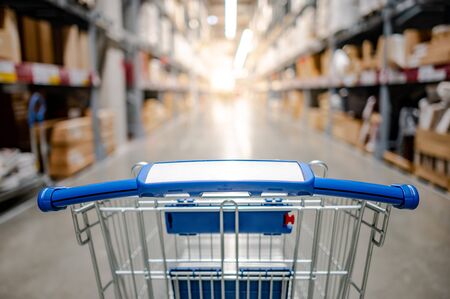 Empty shopping cart or shopping trolley in aisle of supermarket or grocery store. Buying conceptの写真素材