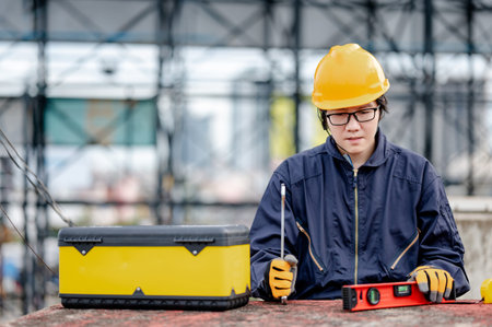 Male Asian mechanic or maintenance worker man wearing protective suit and helmet holding wrench and...
